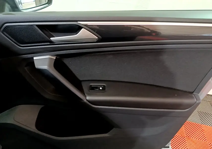 Vue rapprochée de la porte côté gauche du Volkswagen Tiguan 2021 gris foncé, avec poignée argentée et panneau noir.