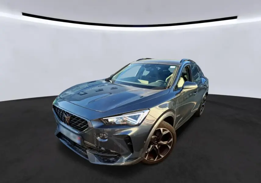 Vue 3/4 avant d’un CUPRA Formentor gris foncé avec jantes noires et calandre distinctive, sur fond neutre.