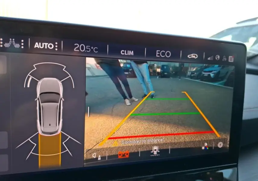 Vue de l'écran de caméra de recul du CUPRA Formentor gris foncé, avec guidage de trajectoire et personnes visibles derrière.