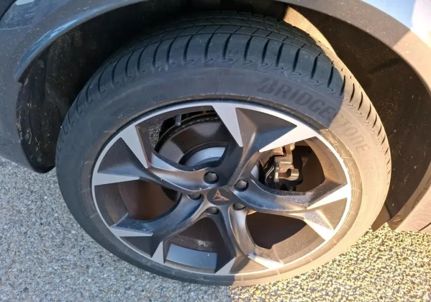 Gros plan sur la roue avant droite du CUPRA Formentor gris foncé, mettant en valeur la jante alliage et le pneu Bridgestone.