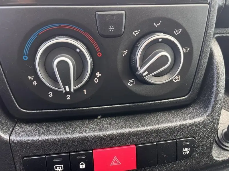Gros plan sur les commandes de climatisation et les boutons de sécurité du tableau de bord du Citroën Jumper blanc Icy.