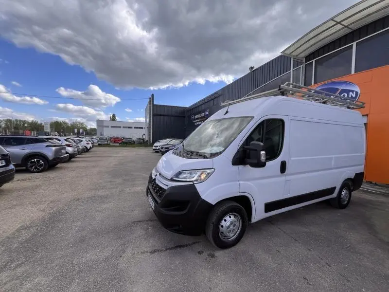 Fourgon Citroën Jumper blanc Icy vu en 3/4 avant droit, avec galerie de toit et portes latérales visibles.