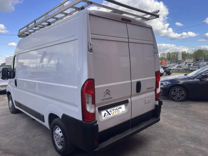 Vue 3/4 arrière droite du Citroën Jumper blanc Icy avec galerie de toit et portes arrière battantes ouvertes.