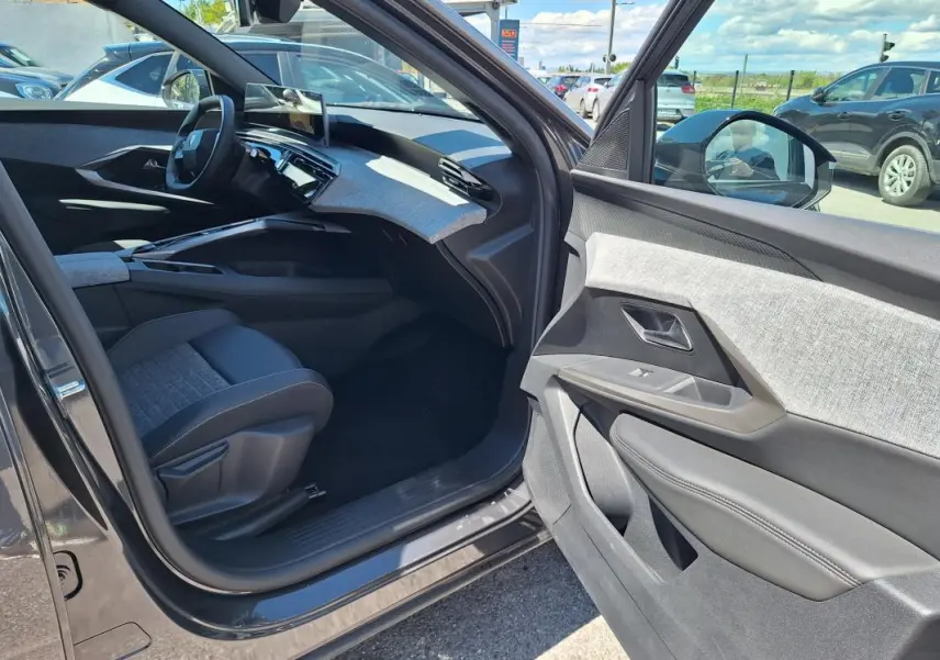 Intérieur côté passager du Peugeot 3008 Hybrid gris foncé 2025, avec tableau de bord moderne et sellerie bicolore.