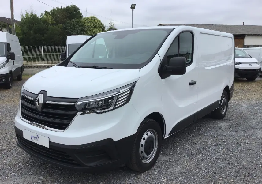 Renault Trafic Fourgon blanc en 3/4 avant droit, avec calandre noire et phares LED distinctifs.