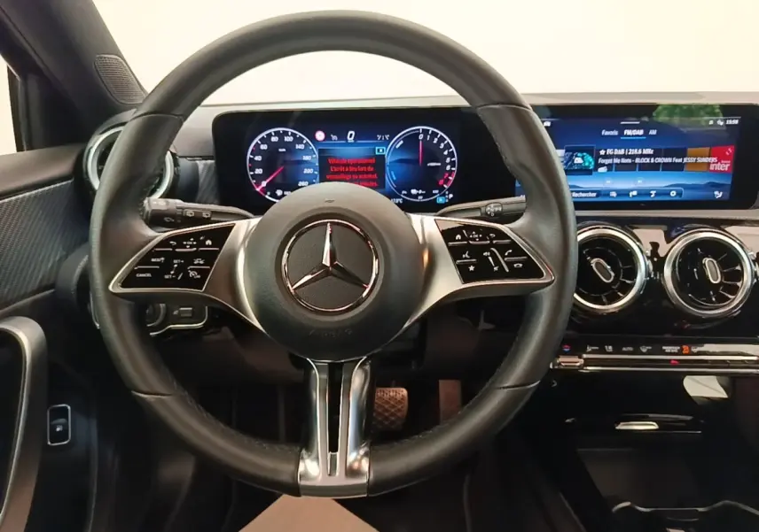 Vue intérieure centrée sur le volant cuir noir et les écrans digitaux larges du tableau de bord de la Mercedes Classe A 250 e.