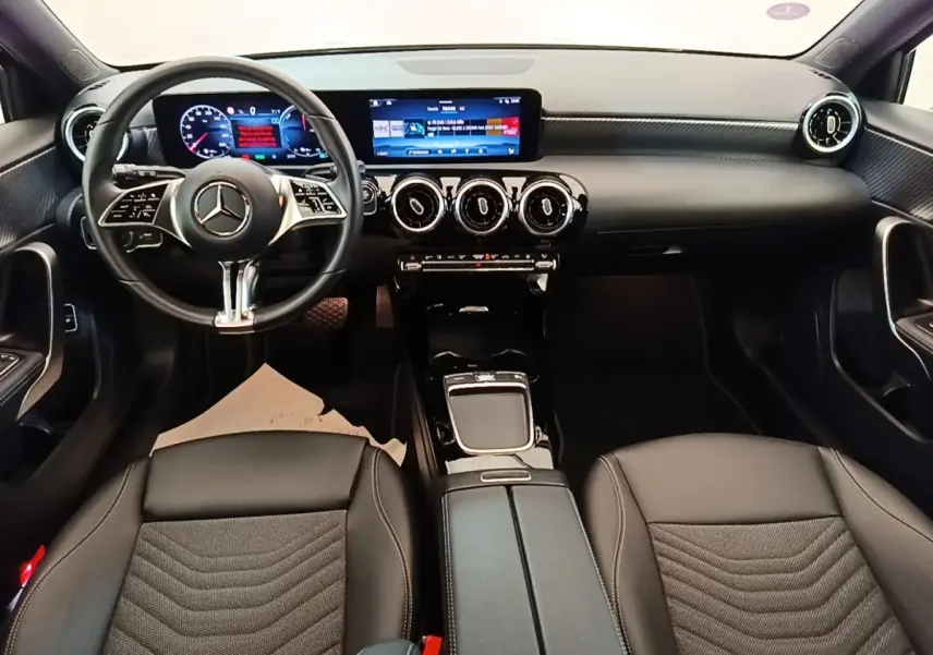 Vue intérieure avant de la Mercedes Classe A 250 e Business Line 2023, tableau de bord noir avec écran tactile et volant cuir.