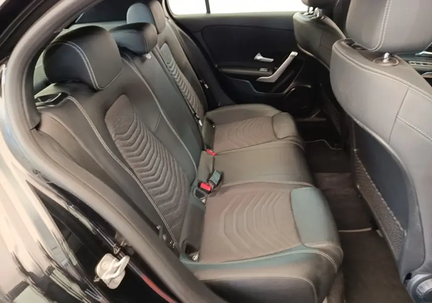 Vue intérieure côté gauche montrant la banquette arrière noire avec surpiqûres blanches de la Mercedes Classe A 250 e 2023.