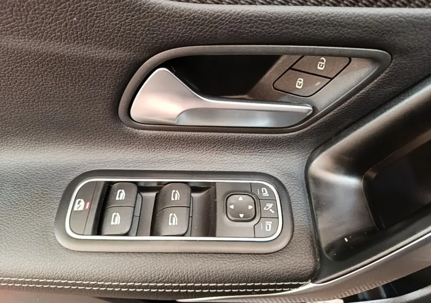Gros plan sur la commande des vitres et poignée intérieure en cuir noir sur la porte côté gauche de la Mercedes Classe A 250 e.
