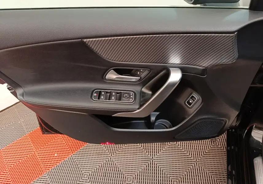 Porte côté conducteur de Mercedes Classe A 250 e Business Line 2023 noire, avec insert carbone et commandes électriques.