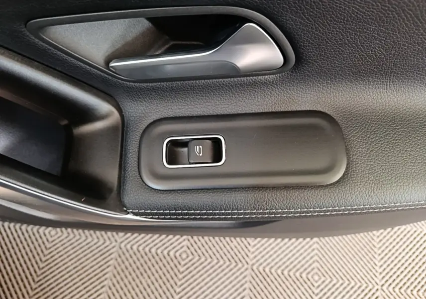Gros plan sur la commande de lève-vitre côté conducteur en cuir noir avec surpiqûres blanches dans une Mercedes Classe A 2023.