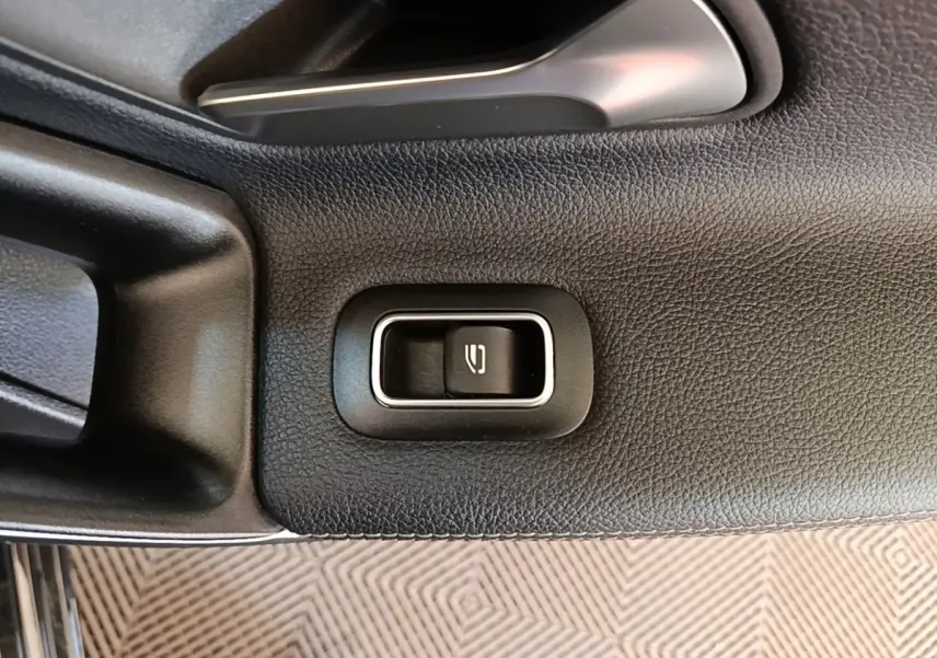 Détail de la commande d'ouverture du coffre sur la porte intérieure noire d'une Mercedes Classe A 250 e Business Line 2023.
