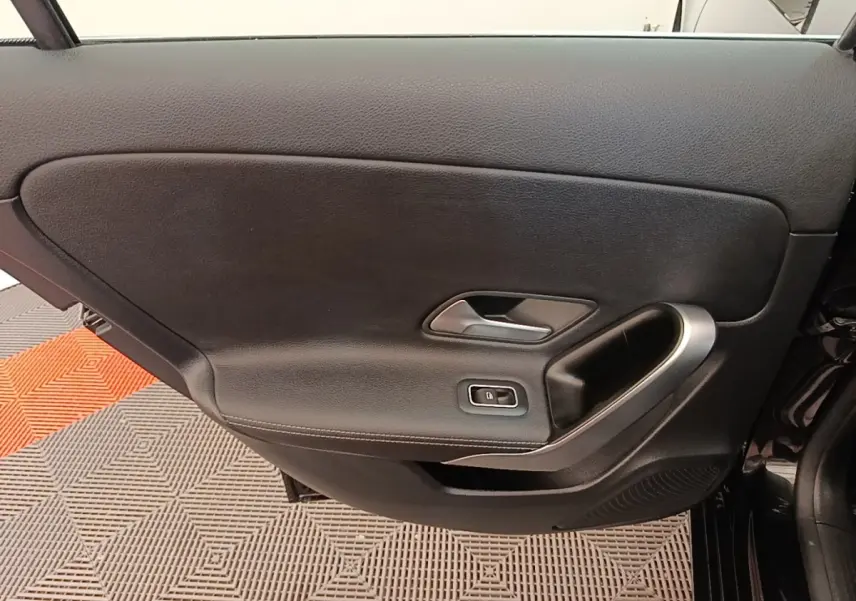 Porte intérieure côté gauche noire de la Mercedes Classe A 250 e Business Line 2023 avec poignée argentée et bouton de verrouillage.
