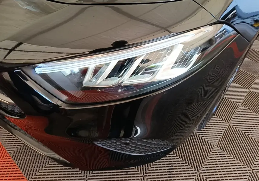 Gros plan sur le phare avant droit LED d'une Mercedes Classe A 250 e Business Line noire, vue en léger angle.