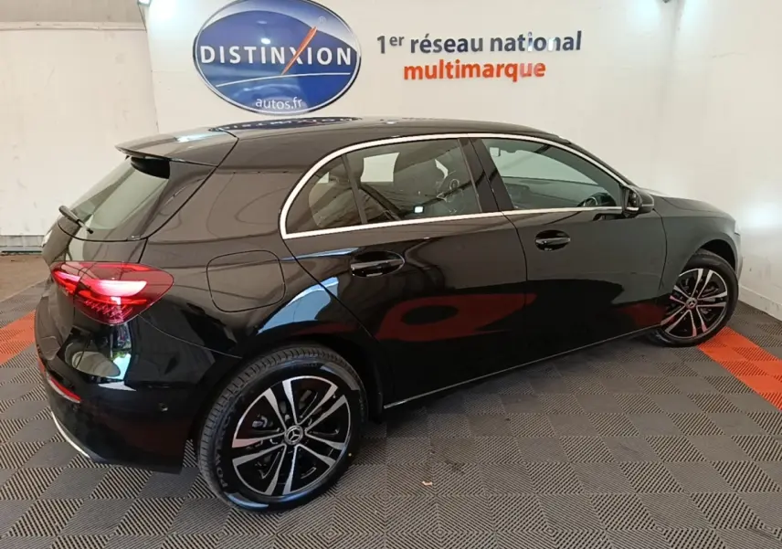 Vue 3/4 arrière droite d'une Mercedes Classe A 250 e Business Line noire avec jantes alliage et feux LED allumés.