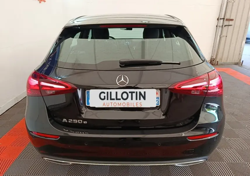 Vue arrière d'une Mercedes Classe A 250 e Business Line noire avec feux arrière LED allumés dans un garage.