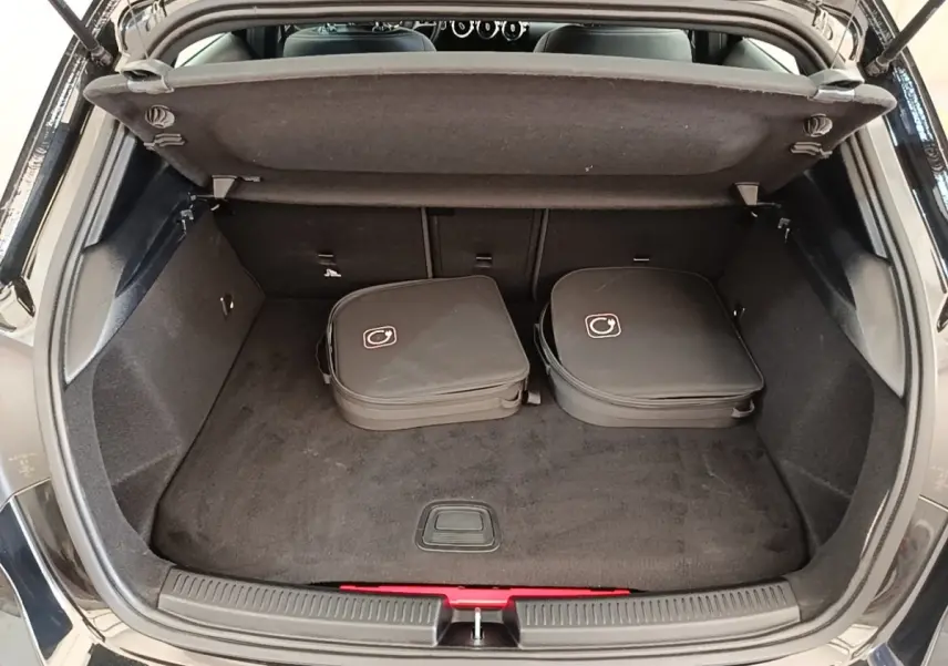 Coffre ouvert d'une Mercedes Classe A 250 e Business Line noir, avec deux sacs de charge posés à l'intérieur.