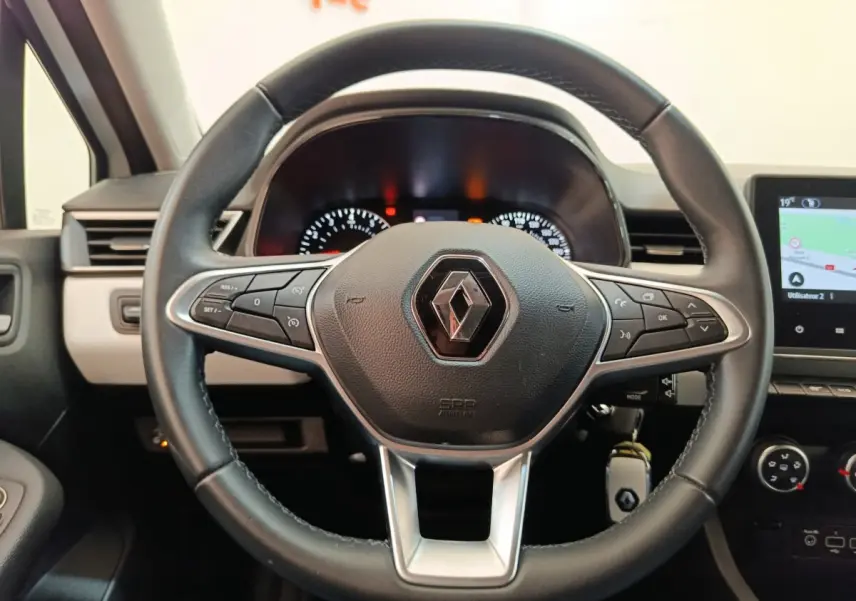 Vue rapprochée du volant en cuir synthétique noir de la Renault Clio 2023 avec tableau de bord et écran tactile visible.