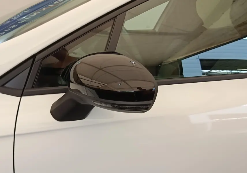 Rétroviseur droit noir brillant sur Renault Clio blanche vue de profil côté conducteur.