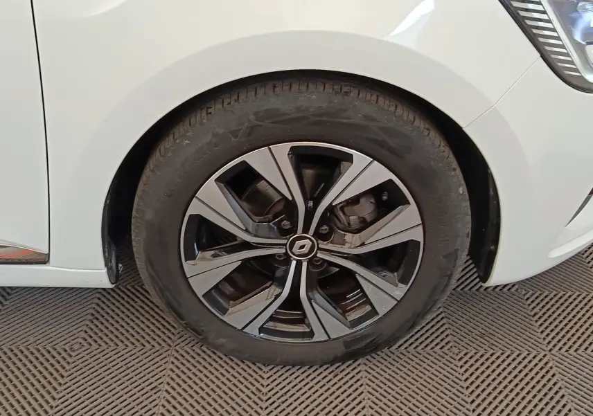 Gros plan sur la roue avant droite de la Renault Clio blanche, avec jante alliage bicolore et logo central Renault.
