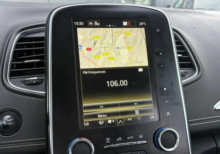 Écran tactile central du Renault Grand Scénic IV avec navigation et réglages climatisation, entouré d'aérateurs noirs.