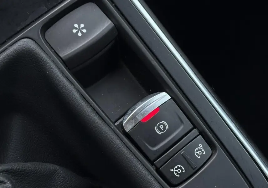 Gros plan sur la console centrale noire du Renault Grand Scénic IV avec frein de parking électrique et commandes de régulateur.