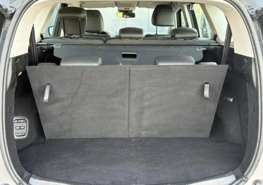 Coffre ouvert vu de l'arrière du Renault Grand Scenic gris Cassiopée, montrant la troisième rangée de sièges relevée.