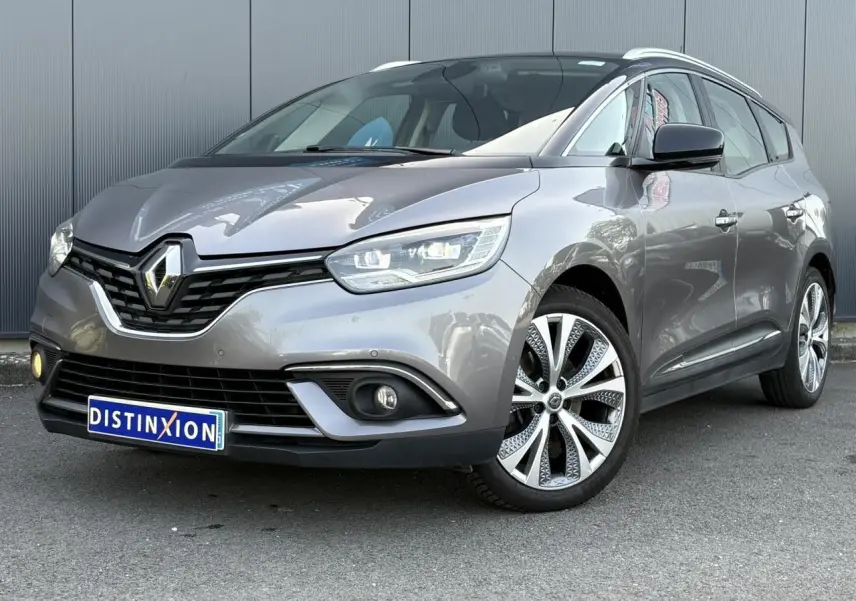 Renault Grand Scenic IV gris Cassiopée en 3/4 avant droit, avec jantes alliage 20 pouces et barres de toit chromées.