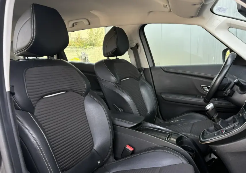 Vue intérieure côté avant droit du Renault Grand Scenic 2021, sièges noirs avec surpiqûres blanches et levier de vitesse manuel.