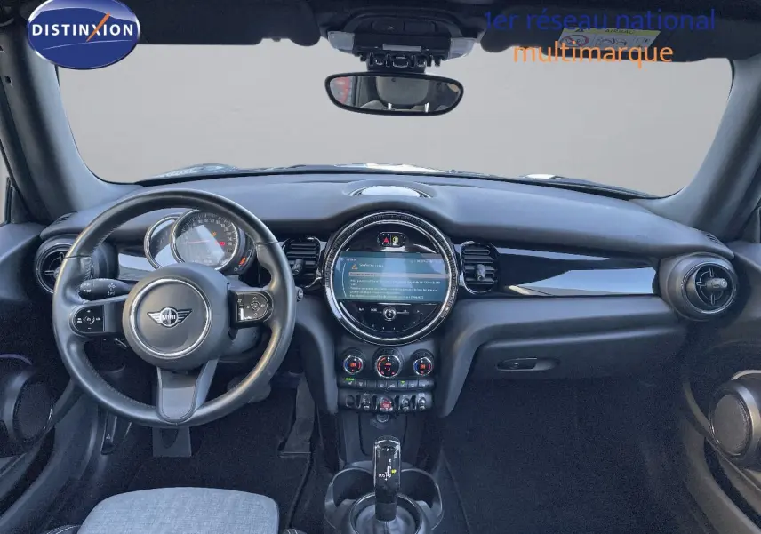 Vue intérieure du tableau de bord et volant noir d'une MINI Cabriolet F57 2023 avec écran central rond et commandes climatiques.