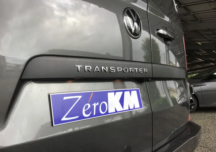 Gros plan sur l'arrière gris anthracite du Volkswagen Transporter T7 avec logo et plaque Zéro KM visible.