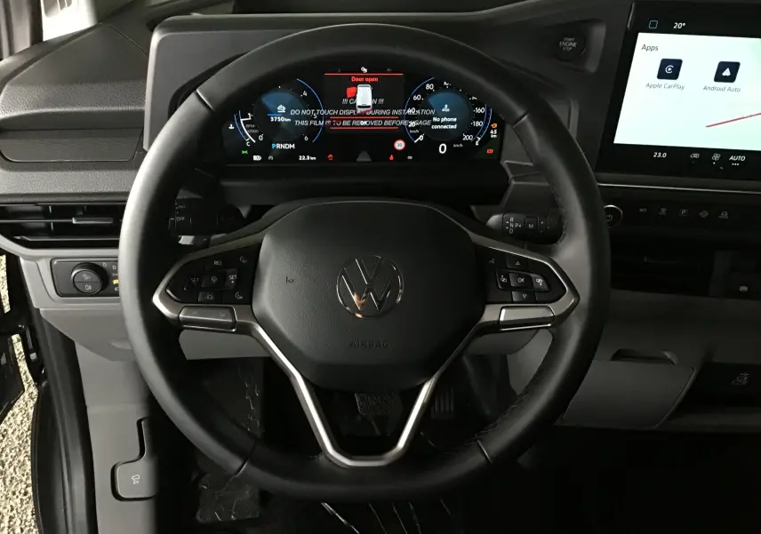 Vue rapprochée du volant multifonction et du tableau de bord numérique du Volkswagen Transporter T7 gris anthracite, intérieur moderne.