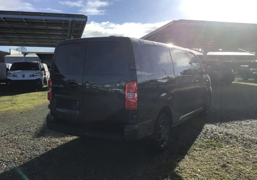 Vue 3/4 arrière droite d'un Citroën Jumpy cabine approfondie gris titane stationné sur un sol gravillonné.
