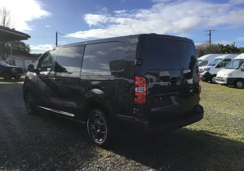 Vue 3/4 arrière droite d'un Citroën Jumpy cabine approfondie gris titane avec vitres teintées et jantes noires.
