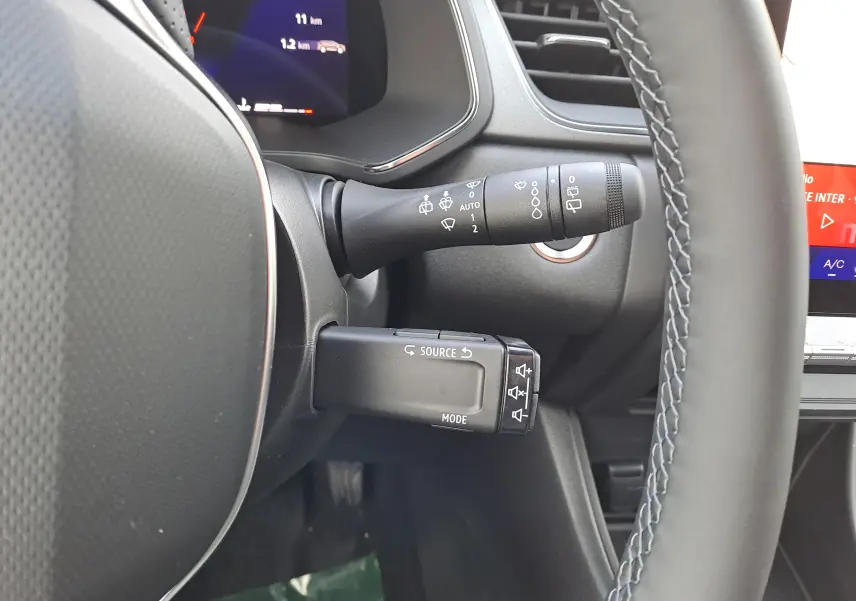Gros plan sur la commande multifonction à gauche du volant du Renault Symbioz gris Cassiopée, tableau de bord partiellement visible.