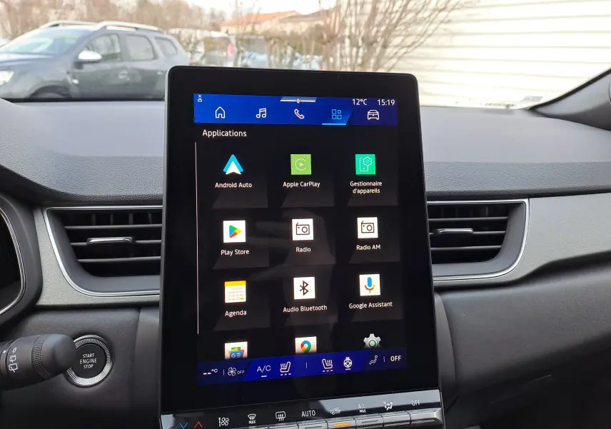 Vue intérieure centrée sur l'écran tactile du tableau de bord du Renault Symbioz gris Cassiopée, affichant les applications connectées.