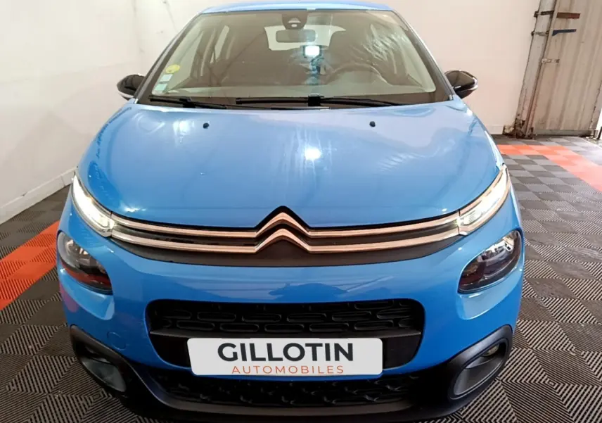 Vue frontale d'une Citroën C3 bleu vif avec feux LED et calandre noire dans un garage.
