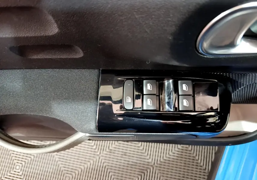 Commande des vitres électriques sur la porte côté conducteur d'une Citroën C3 bleu 2017, intérieur noir.