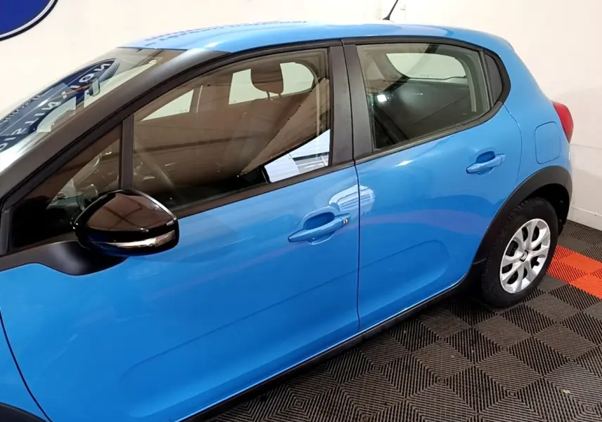 Vue latérale côté gauche d'une Citroën C3 bleu vif, avec rétroviseur noir et poignées de porte assorties.