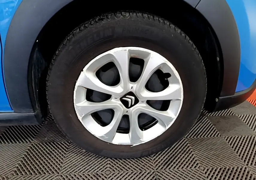 Gros plan sur la roue avant gauche de la Citroën C3 bleu avec jante alliage et logo Citroën central.