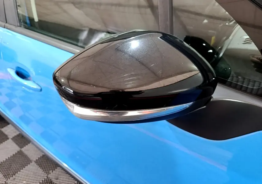 Rétroviseur noir brillant côté gauche d'une Citroën C3 bleu 2017, avec clignotant intégré visible.