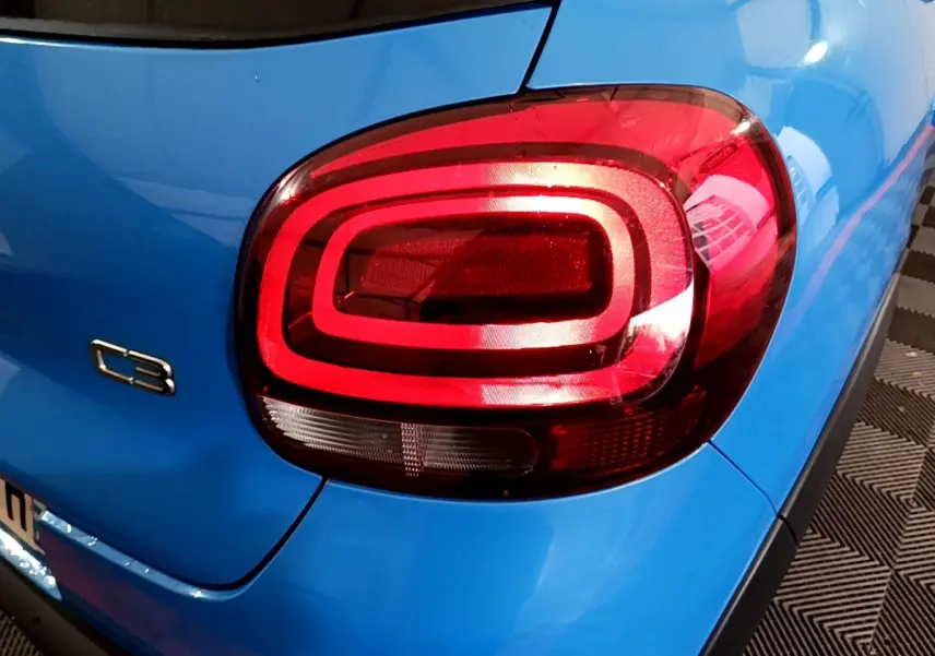 Gros plan sur le feu arrière droit rouge d'une Citroën C3 bleue 2017, avec logo C3 visible sur la carrosserie.