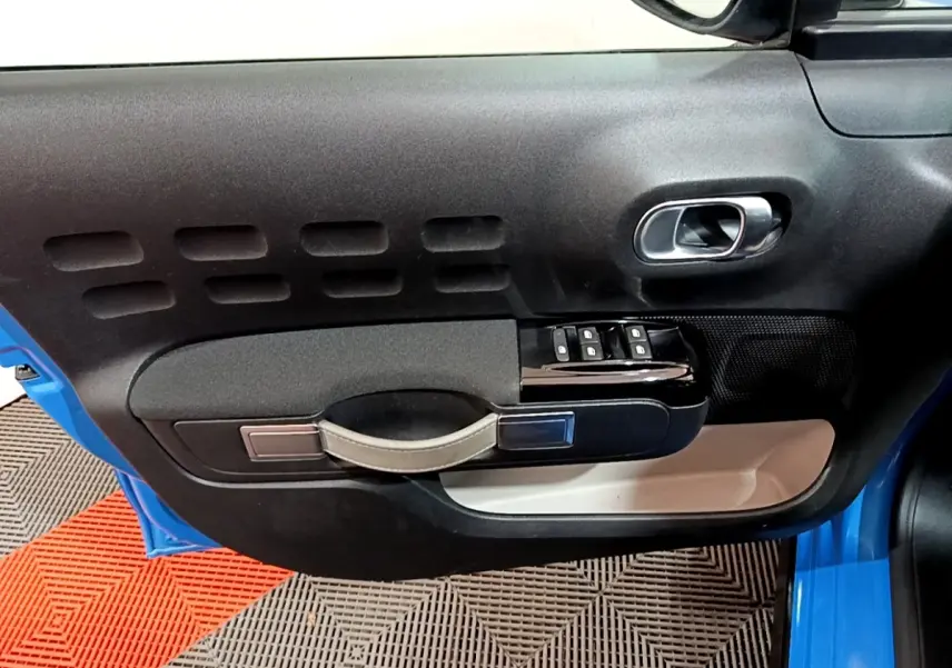 Gros plan sur la porte avant gauche bleu de la Citroën C3 2017, avec commandes de vitres et poignée intégrée.