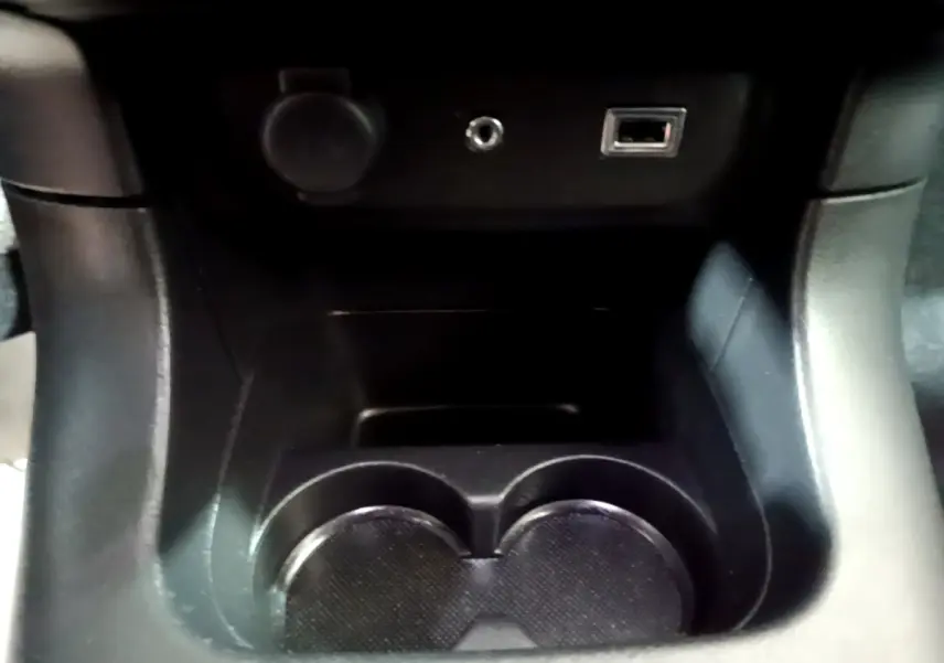 Gros plan sur la console centrale noire de la Citroën C3 BlueHDi 2017, montrant porte-gobelets et prises USB et 12V.