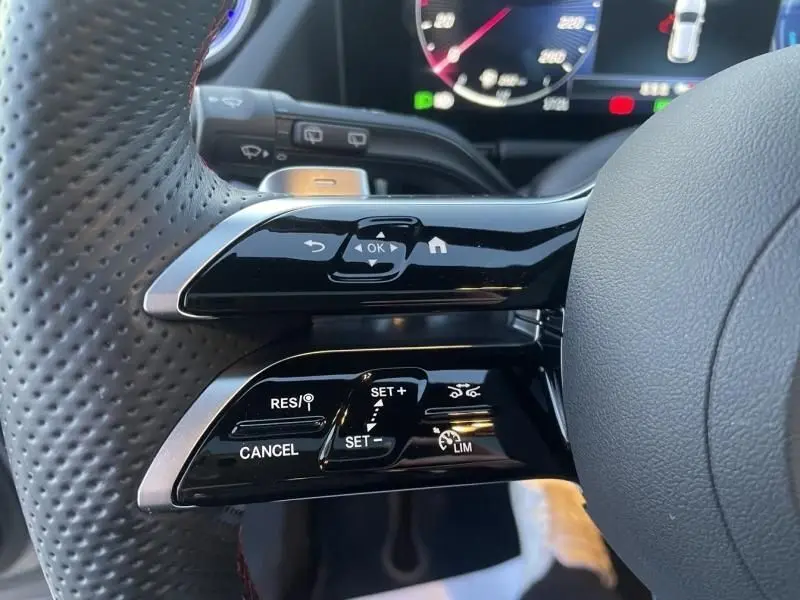 Gros plan sur les commandes au volant à gauche du Mercedes GLA 250 e AMG Line 2025, avec finition noire brillante et cuir perforé.