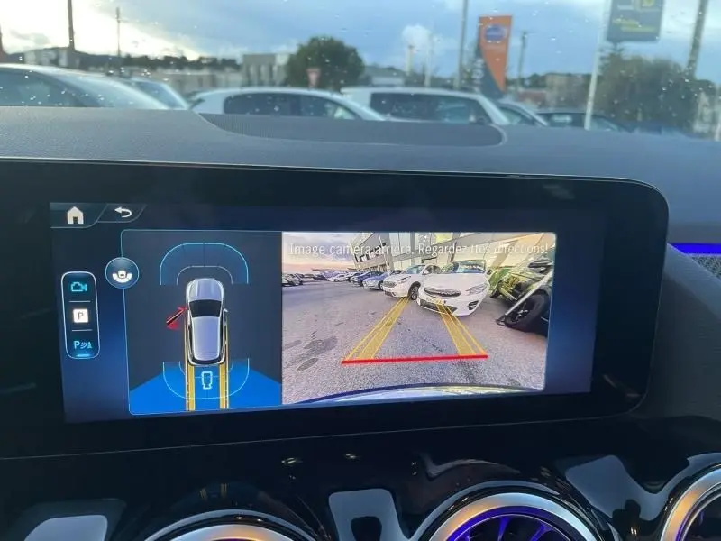 Vue intérieure de l'écran multimédia du Mercedes GLA 250 e 2025, affichant la caméra de recul avec lignes de guidage jaunes.