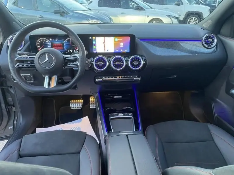 Vue intérieure avant du Mercedes GLA 250 e AMG Line 2025, avec tableau de bord numérique et éclairage d’ambiance bleu.