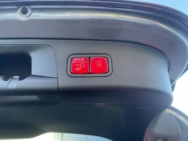 Gros plan sur les boutons rouges d’ouverture et de verrouillage électrique du hayon du Mercedes GLA 250 e gris foncé métal.