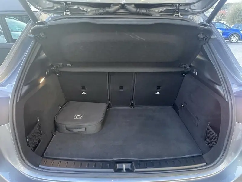 Coffre ouvert vu de l'arrière d'un Mercedes GLA 250 e AMG Line gris foncé métal avec sac de rangement noir.