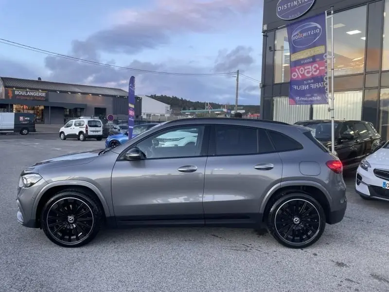 Vue de profil côté gauche d’un Mercedes GLA 250 e AMG Line gris foncé métal avec jantes noires, stationné en extérieur.